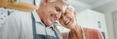 Lächelndes älteres Ehepaar in der Küche beim Kochen